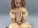 a close up of a doll sitting on a grey surface