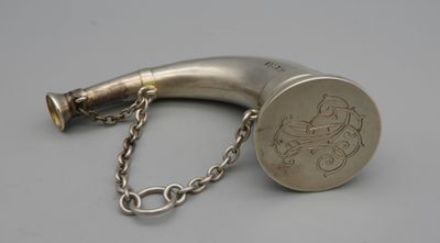 une vieille pipe en argent entourée d'une chaîne, posée sur une surface grise