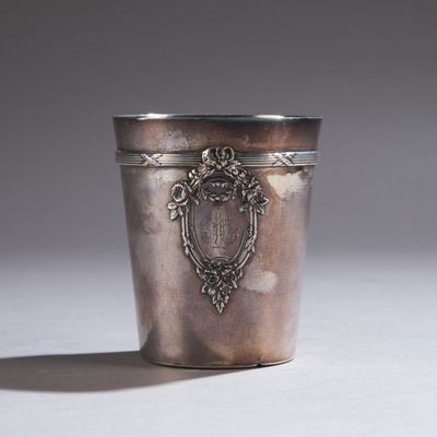 une coupe en argent ancienne posée sur une table blanche