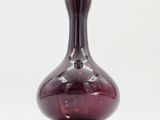 a close up of a red glass vase on a wooden stand