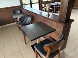 tables and chairs in a restaurant with a bar in the background