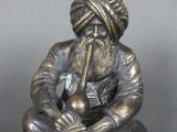 une vieille figurine en bronze représentant un homme barbu coiffé d'un turban