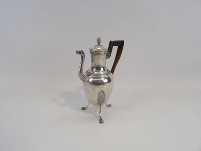 une cafetière ancienne en argent, posée sur un support et dotée d'une poignée en bois
