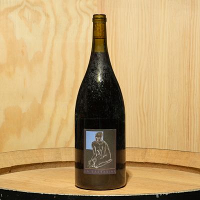 a bottle of wine sitting on top of a barrel