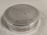 une boîte ancienne plaquée argent posée sur une surface blanche