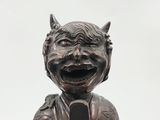 a statue of a devil holding a cell phone in his hand