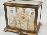 an antique brass and glass display case with a lot of glasses in it