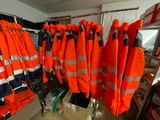 many orange life jackets hanging on a rack in a room