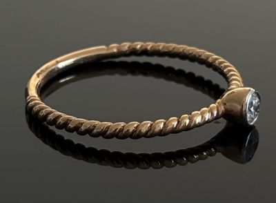 une image représentant une bague en or sertie d'un diamant, posée sur une surface noire