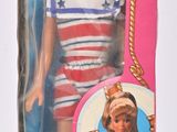 une poupée dans une boîte rose sur laquelle figure l'image d'une petite fille en tenue de marin