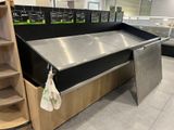 a stainless steel counter in a store with shelves on both sides