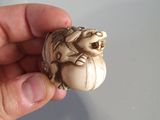 a hand holding a piece of ivory with a frog on it