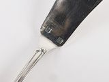 a silver spoon with a black handle sitting on a white surface