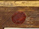 a red wax seal on a piece of wood