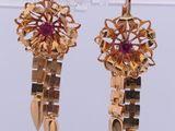 une paire de boucles d'oreilles en or et rubis exposée dans une vitrine