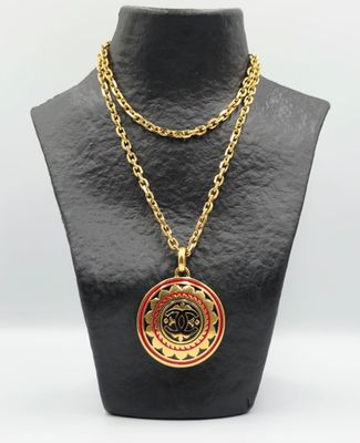 un collier en or orné d'un médaillon rouge sur un mannequin noir