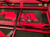a red machine that is working on a piece of metal