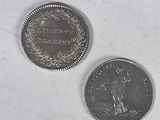 two coins sitting next to each other on a white surface