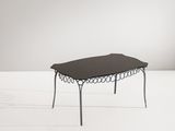 La table est en métal et possède un plateau en verre noir.