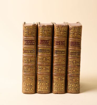 trois vieux livres posés l'un sur l'autre sur une surface blanche