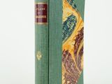un vieux livre à la couverture verte posé sur une surface blanche