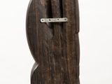 a wooden sculpture on a white pedestal with a white background