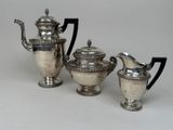 three silver teapots and a creamer on a table