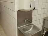 a stainless steel sink in a public restroom with a paper towel dispenser