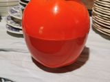 une grosse pomme rouge posée sur une table où se trouvent de nombreuses assiettes