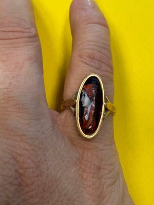 quelqu'un tient une bague sur laquelle est gravée la photo d'un homme