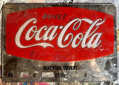 a coca cola sign sitting on top of a pile of newspapers
