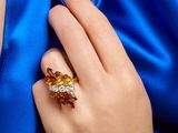 une personne vêtue d'une robe bleue tenant une bague sertie d'une pierre jaune et blanche