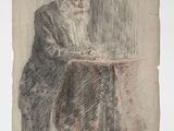 un vieil homme assis à une table, un livre sur les genoux
