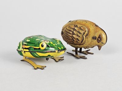 two figurines of birds and a frog on a white surface