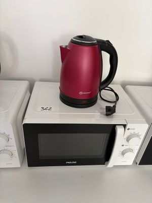 trois micro-ondes empilés les uns sur les autres sur une étagère