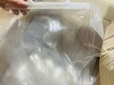 a person that is holding a plastic bag over a couch
