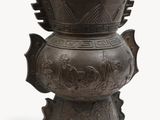 a large metal vase with a bird design on it