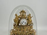 une horloge en or sous un dôme de verre sur une table