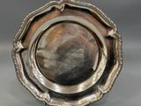 a silver plate on a stand on a gray surface