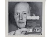 black and white photograph of a man holding a camera in front of his face
