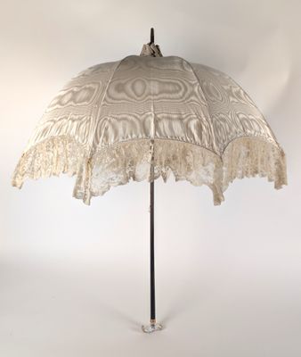 un parapluie en dentelle posé sur un support, devant un fond blanc