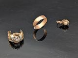 trois bagues en or et une bague ornée d'une perle sur un fond noir