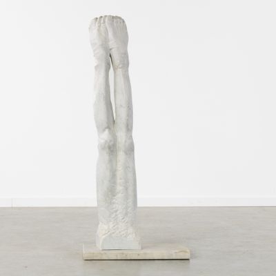 une sculpture blanche représentant une femme les mains levées vers le ciel