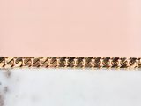 a close up of a gold chain bracelet on a marble surface