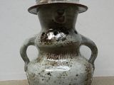 un vase blanc surmonté d'un chapeau