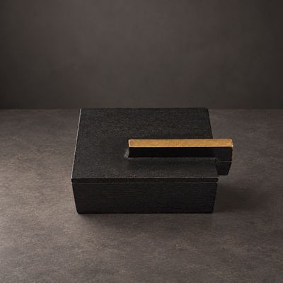 une boîte noire posée sur une table près d'un mur noir