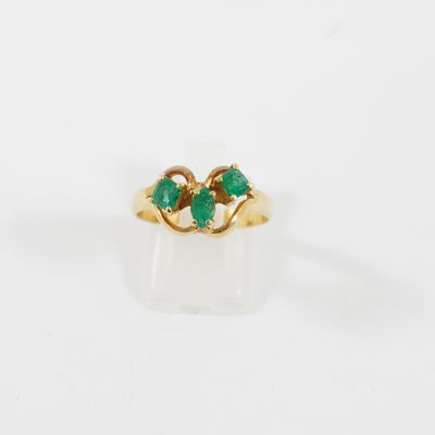 un gros plan d'une bague en or sertie de deux émeraudes