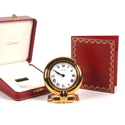 a small gold clock in a red box with a white face