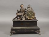 une statue représentant un homme assis sur une table, avec une horloge