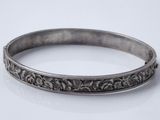 gros plan d'un bracelet en argent sur une surface blanche